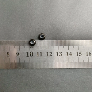 Close-up of black stainless steel earring backs with metric scale showing 6mm diameter
