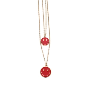 Dettaglio macro della collana a doppio strato in oro e ciondoli smiley in smalto rosso