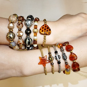 Dettaglio di bracciali bohémien sovrapposti con perle leopardate e accenti dorati