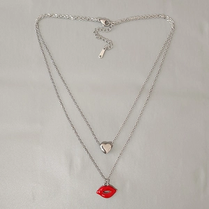 Macro detail of double-layer stainless steel necklace with red lip and heart charms