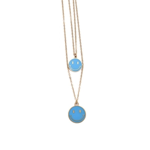 Dettaglio di una collana dorata a doppio strato con ciondoli smiley in smalto celeste