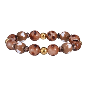 Dettaglio del bracciale con perle leopardate, cuori bianchi e sfere metalliche dorate