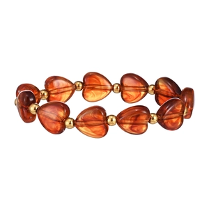 Dettaglio delle perle a cuore in resina ambrata e sfere dorate su un bracciale vintage