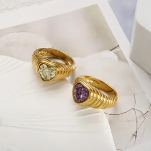 Nahaufnahme von vergoldeten Croissant-Ringen mit gelbem und violettem Herz-Kristall