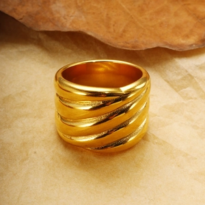 Nahaufnahme eines breiten 18K vergoldeten Rings mit Spiralstruktur auf Papierhintergrund