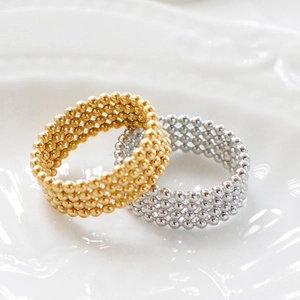 Minimalist beaded stackable rings in gold and silver finish on a white textured plate