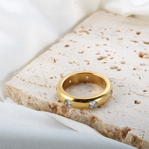 Ring aus 18K vergoldetem Edelstahl mit klaren Zirkonsteinen auf beigem Stein
