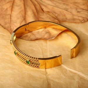 Retro gold cuff bracelet featuring green zircon stones and geometric hollow grid design