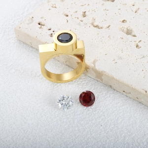 Dettaglio dell'anello dorato a vite con pietre intercambiabili nere, bianche e rosse
