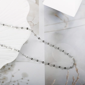 Collier en acier titane argenté poli sur un plateau blanc en forme de coquillage