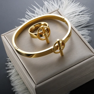Détail d'un ensemble bracelet et bague dorés avec fermoir OT sur une boîte à bijoux élégante