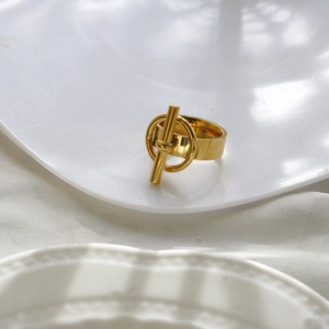 Vue détaillée d'une bague en acier doré avec fermoir OT posée sur une assiette en céramique