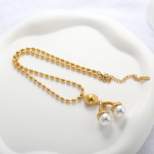 Détail d'un collier à perles dorées avec pendentif fer à cheval et poinçon K18