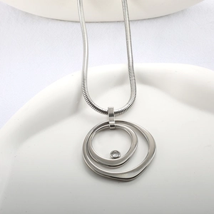 Détail macro de la chaîne serpent argentée et pendentif double anneau avec strass