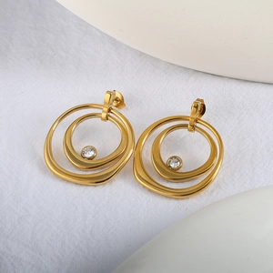 Gros plan de boucles d'oreilles doubles anneaux dorés avec zircone sur lin blanc