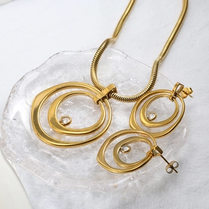 Détail du collier à chaîne serpent dorée et boucles d'oreilles cercles concentriques avec cristal
