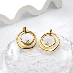 Vue macro de boucles d'oreilles minimalistes à double anneau doré avec un zircon serti