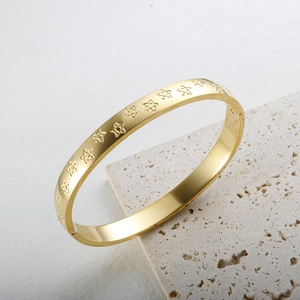 Detalle de brazalete dorado con bisagra y patrones de estrellas en relieve continuos