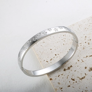Primer plano de brazalete plateado con estrellas grabadas sobre piedra natural