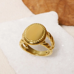 Detailed view of an oval gold ring with twisted rope band on a white stone background