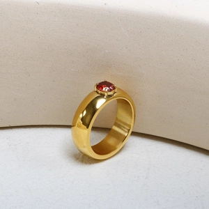 Vue macro d'une bague en acier doré ornée d'un cristal rouge serti à quatre griffes