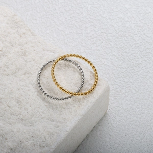 Makroaufnahme minimalistischer gedrehter Ringe in 18K Gold und Silber aus Edelstahl