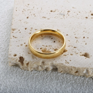 Minimalist 4mm 18K gold plated band ring displayed on a textured stone tray
