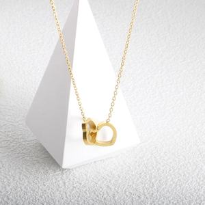 Detailed close-up of interlocking gold-plated double hearts necklace with pearl luster inlay