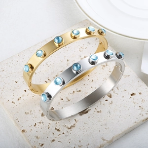 Detail van goud en zilver roestvrijstalen armbanden met blauwe zirkonia op stenen blad