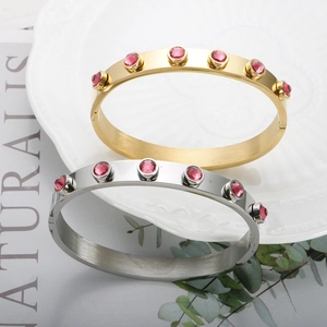 Detailopname van goud- en zilverkleurige roestvrijstalen armbanden met roze zirkoon