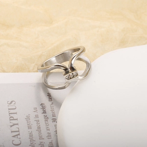 Macro shot of silver geometric hollow ring with micro-set diamonds on white stone tray