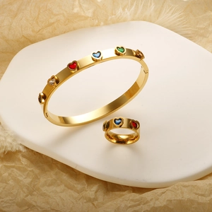 Gold stainless steel jewelry set with colorful heart stones on white stone slab