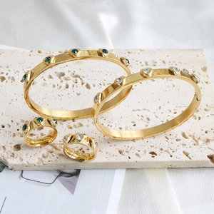 Polished gold heart-shaped gemstone bracelet and ring sets on a stone base