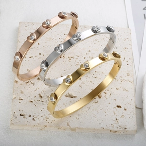 Polished 18K gold stainless steel bangle set with crystal hearts on beige stone