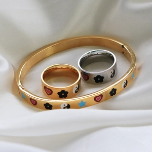 Close-up of gold and silver steel jewelry set with colorful enamel heart and star patterns