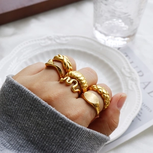 Five-piece set of gold wavy and braided stainless steel rings on a model hand
