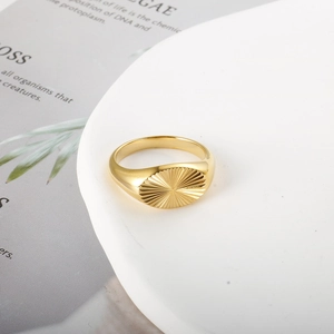 Macro detail of golden wave pattern ring with sunburst texture on a minimal stand