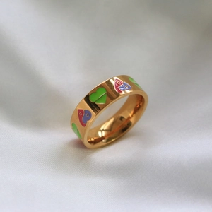 Dettaglio dell'anello largo dorato con cuori in smalto colorato su seta bianca lucida