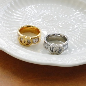 Close-up of interlocked Roman numeral rings with square-cut cubic zirconia in a ceramic dish