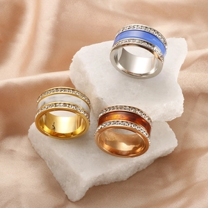 Three-color titanium steel rings with resin inlay and sparkling crystals on white marble