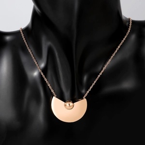 Détail d'un collier en titane or rose avec pendentif géométrique sur un buste noir