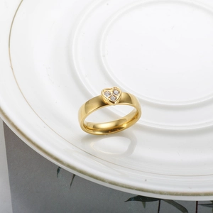 Anello dorato a forma di cuore con tre pietre di zirconia su un vassoio di ceramica bianca