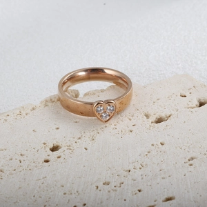 Dettaglio anello a cuore in oro rosa con tre zirconi su pietra testurizzata