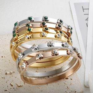Stack of gold, silver, and rose gold stainless steel bangles with sparkling floral zircon studs