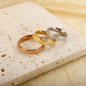 Detailed view of matte frosted gold, silver and rose gold rings on a travertine stone