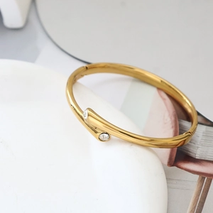 Details des vergoldeten Titanstahl-Scharnierarmbands mit zwei Zirkonia-Kristallen