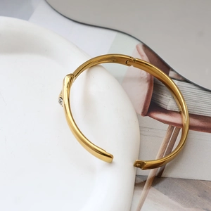 Detailansicht eines dünnen vergoldeten Titan-Armbands mit einem kleinen funkelnden Zirkon