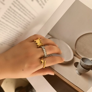 Detail of stacked irregular geometric rings with snake wrap and zircon stone designs