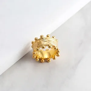 Macro shot of gold irregular textured ring with metallic beads on marble background