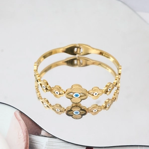 Detailansicht der goldenen Evil Eye Manschette mit blauen Emaille-Akzenten im Spiegel